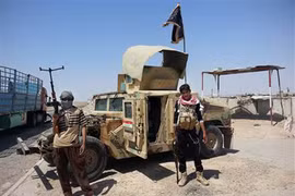 Phiến quân IS đứng cạnh một xe Humvee chiếm được của Iraq tháng 6/2014. Ảnh: AP