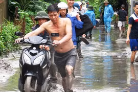 Người dân phải lội bùn, di dời một số vật dụng ra khỏi khu vực ngập. Ảnh: Giang Chinh.