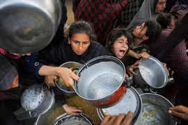 Người Palestine tụ tập để nhận thức ăn do một bếp từ thiện nấu ở Khan Younis, phía nam Dải Gaza, ngày 17/1. Ảnh: Reuters.