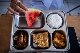 Một học sinh trung học cơ sở ở Bandung, Indonesia cùng khay thức ăn được cung cấp như một phần trong chương trình bữa ăn miễn phí của nước này. Ảnh: CNA.