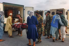 Binh lính Taliban và thường dân đưa nạn nhân động đất lên xe cứu thương tại sân bay ở Jalalabad, Afghanistan ngày 1/9. Ảnh: Reuters.