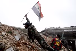 Một binh sĩ trong quân đội của chính phủ Syria cắm lá cờ quốc gia trong một trận chiến với các nhóm phiến quân tại tiền tuyến Ramouseh nằm tại phía đông thành phố Aleppo vào ngày 5.12.2016.