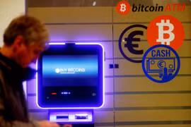 Một người đàn ông đi ngang qua một cây ATM bitcoin ở Vilnius, Litva. Ảnh: CNBC