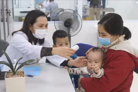 Nhân viên y tế kiểm tra nhiệt độ cho trẻ (Ảnh - Minh Thuý) 