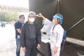 Nhân viên y tế kiểm tra thân nhiệt cho người dân (Ảnh: Minh Thuý) 