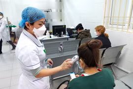 Bác sĩ đo nhiệt độ cơ thể cho người bệnh. Ảnh: Minh Thúy