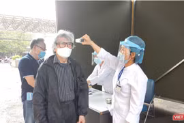 Nhân viên y tế kiểm tra nhiệt độ cho người dân (Ảnh - Minh Thuý) 