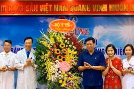 Thứ trưởng Bộ Y tế Đỗ Xuân Tuyên (áo xanh) chúc mừng em bé đầu tiên ra đời bằng kỹ thuật thụ tinh trong ống nghiệm. (Ảnh: Thảo Nguyên)