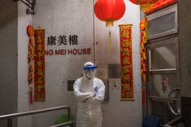 Một nhân viên y tế mặc đồ bảo hộ đứng bảo vệ bên ngoài lối vào tòa nhà chung cư ở Tsing Yi (Hồng Kông) sau khi phát hiện cư dân thứ hai nhiễm virus tại đây. Hơn 100 người sống tại tòa chung cư này đã được sơ tán (ảnh Getty Images)