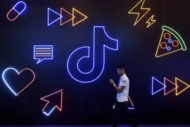 Một người đàn ông cầm điện thoại đi ngang qua biển hiệu có logo ứng dụng Douyin của ByteDance tại Hàng Châu, tỉnh Chiết Giang, Trung Quốc. (Ảnh:SCMP)