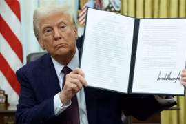 Tổng thống Mỹ Donald Trump cầm một sắc lệnh hành pháp đã ký về tiền điện tử. Ảnh: Reuters.