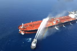 Một tàu của Iran cố gắng dập lửa cho con tàu bị tấn công trên vịnh Oman (Ảnh: Reuters)
