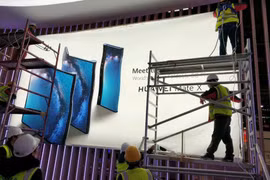 Các công nhân đang thi công poster quảng cáo điện thoại Huawei Mate X (ảnh: Phone Arena)