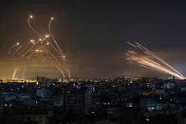 Tên lửa của Hamas phóng từ Dải Gaza (phải) và hệ thống Vòm Sắt phóng tên lửa đánh chặn (trái). Ảnh: AFP.