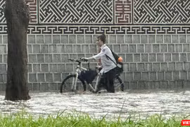 Một nữ sinh ướt hết quần áo khi di chuyển trên tuyến đường ngập sâu ở Hà Nội.