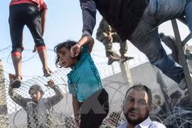 Người tị nạn Syria vượt qua hàng rào dây thép gai tại biên giới Thổ Nhĩ Kỳ. 