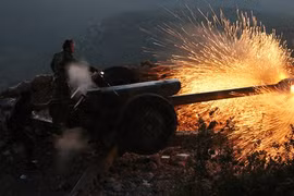 Một binh sĩ quân đội chính phủ Syria vận hành một khẩu pháo trong một cuộc tập trận tại Latakia, Syria.