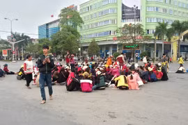 Người dân Sầm Sơn ngồi la liệt dưới lòng đường ngã tư đại lộ Lê Lợi - Trần Phú. Ảnh: Nguyễn Dương.