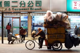 Một người đàn ông đang đạp xe qua một khu phố mua sắm tại Bắc Kinh. Ảnh:Bloomberg