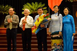 Chủ tịch UBND TP.HCM Nguyễn Thành Phong (giữa) nhận hoa chúc mừng từ ông Lê Hoàng Quân và bà Nguyễn Thị Quyết Tâm - Ảnh: Diệp Đức Minh