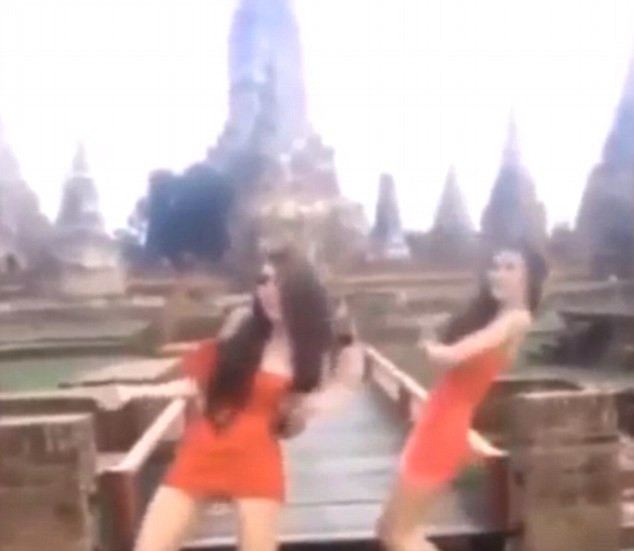 Hai phụ nữ mặc váy cam ngắn cũn nhảy nhót trước đền thiêng