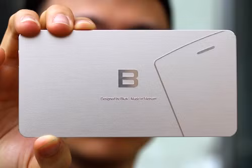 Một phần Bphone lộ diện ở góc bên phải thiệp mời với lỗ loa thoại và góc trái điện thoại bo tròn.