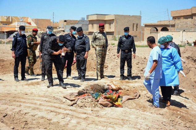 Lực lượng an ninh Iraq cùng nhóm điều tra pháp y xem xét một ngôi mộ tập thể chứa hàng chục thi thể đàn ông, phụ nữ và trẻ em tại sân vận động ở Ramadi, cách Baghdad 115km về phía tây - Ảnh: AP