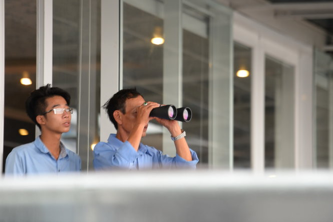 Người dân lên nhà cao tầng quan sát chiếc máy bay US Air Force (C17) -Ảnh: Hữu Khoa