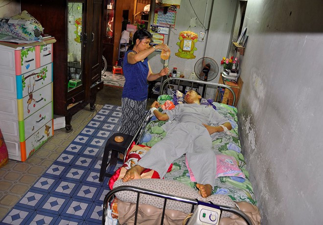 Bà Phạm Thị Thanh cho con trai bị tai nạn lao động ăn cháo bằng đường ống. Ảnh:Ngọc An.