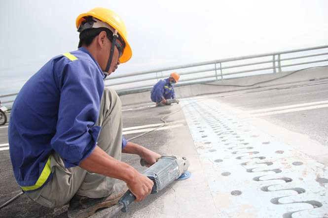 Công nhân đang chùi rửa, mài dũa mặt cầu trước giờ thông xe