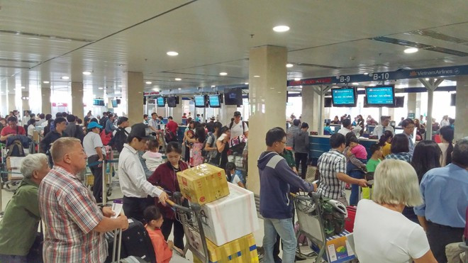 Hành khách xếp hàng dài chờ đợi check-in tại quầy ở sân bay Tân Sơn Nhất.Ảnh: Trường Nguyên.