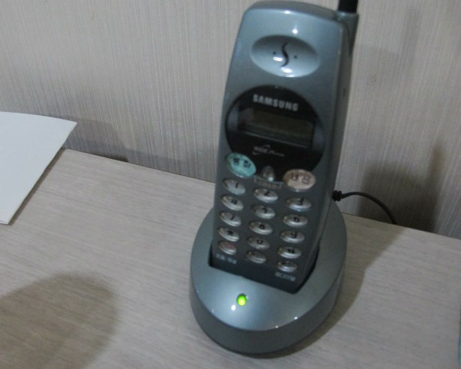 Trên bàn lắp một chiếc điện thoại Samsung đời cổ.