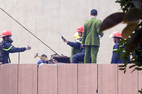 Lực lượng cứu hỏa dùng búa phá tường gạch để tiếp cận khu vực cháy. Ảnh:Phương Sơn.