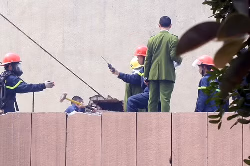 Lực lượng cứu hỏa dùng búa phá tường gạch để tiếp cận khu vực cháy. Ảnh:Phương Sơn.