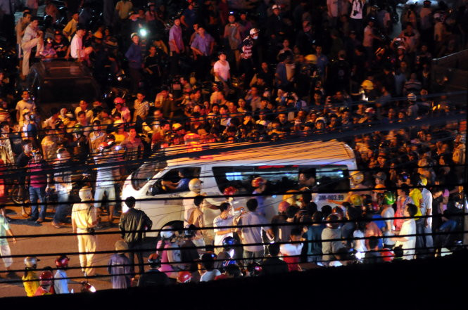 Người dân hiếu kỳ theo dõi kẻ ngáo đá được đưa đi cấp cứu - Ảnh: S ĐỊNH