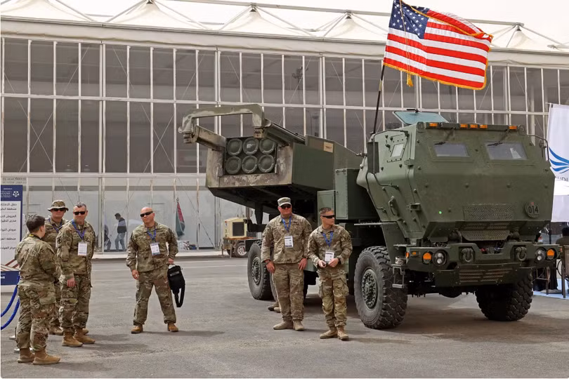 Các quân nhân Mỹ đứng bên Hệ thống Tên lửa Pháo binh Cơ động Cao M142 trong Triển lãm Quốc phòng ở Ả Rập Xê Út (Ảnh: The Drive) Các quân nhân Mỹ đứng bên Hệ thống Tên lửa Pháo binh Cơ động Cao M142 trong Triển lãm Quốc phòng ở Ả Rập Xê Út (Ảnh: The Drive)