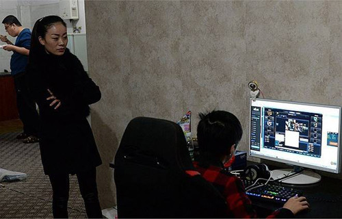 Mẹ của Tiểu Tânđang đứng xem con mình phát sóng trực tiếp buổi chơi game. Ảnh:Nownews.