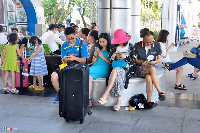 Du khách Trung Quốc ngồi vạ vật cùng hành lý. Ông Trần Sơn Hải - Phó chủ tịch UBND tỉnh Khánh Hòa xác nhận, sân bay Cam Ranh đang quá tải, trong khi đó cơ sở hạ tầng không đáp ứng được nhu cầu.