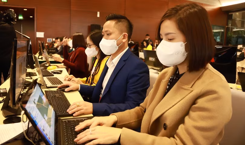 Các phóng viên thực hiện biện pháp phòng, chống dịch khi tác nghiệp tại Trung tâm Báo chí - Đại hội Đảng XIII.