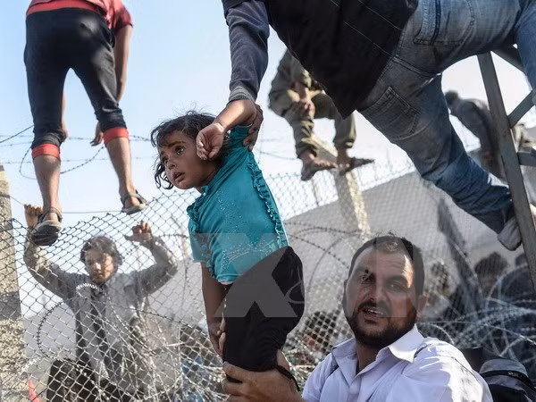 Người tị nạn Syria vượt qua hàng rào dây thép gai tại biên giới Thổ Nhĩ Kỳ. 