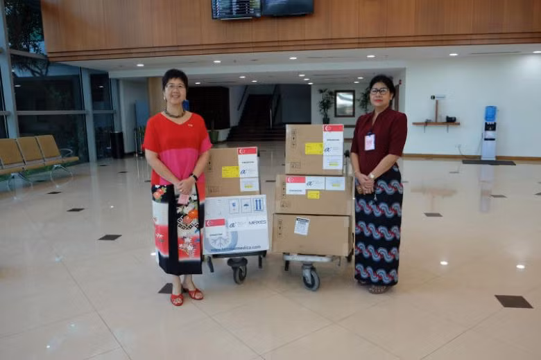 Đại sứ Singapore tại Myanmar - Vanessa Chan (trái) bàn giao các vật tư y tế tài trợ của Singapore cho Giám đốc Phòng thí nghiệm Y tế Quốc gia Myanmar - Htay Htay Tin, bao gồm 3.000 bộ xét nghiệm chẩn đoán và hai máy phản ứng chuỗi Polymerase (PCR) để xét 