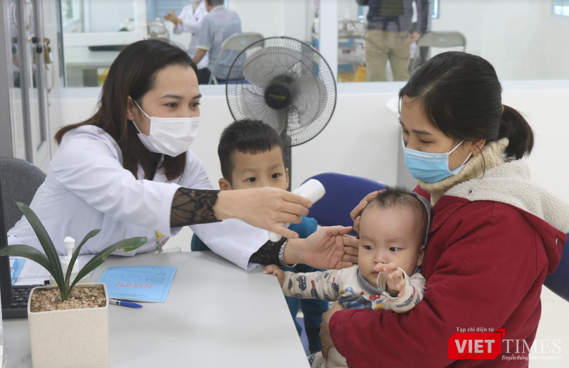 Nhân viên y tế đo nhiệt độ cho trẻ (Ảnh: Minh Thuý)