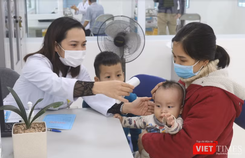 Nhân viên y tế đo nhiệt độ cho trẻ (Ảnh: Minh Thuý)