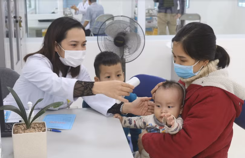 Nhân viên y tế kiểm tra nhiệt độ cho trẻ (Ảnh - Minh Thuý) 