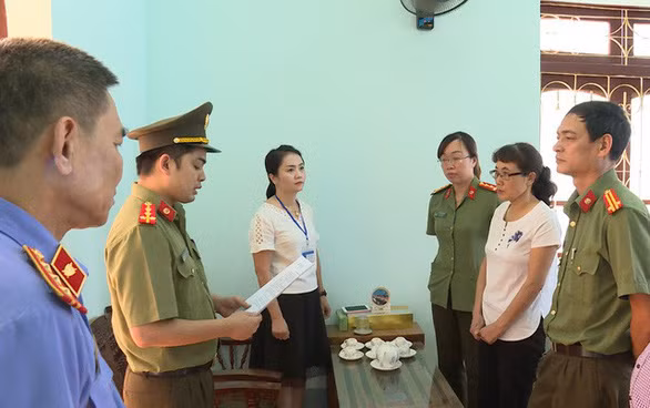 Bà Nguyễn Thị Hồng Nga, chuyên viên Phòng khảo thí và quản lý chất lượng Sở GD-ĐT Sơn La (mặc áo trắng bên phải), nghe tống đạt quyết định khởi tố bị can. 
