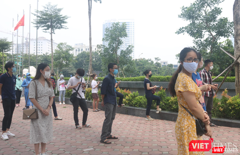 Người dân xếp hàng dài ở vỉa hè bên ngoài điểm tiêm giữa thời tiết nắng nóng (Ảnh - Minh Thuý)