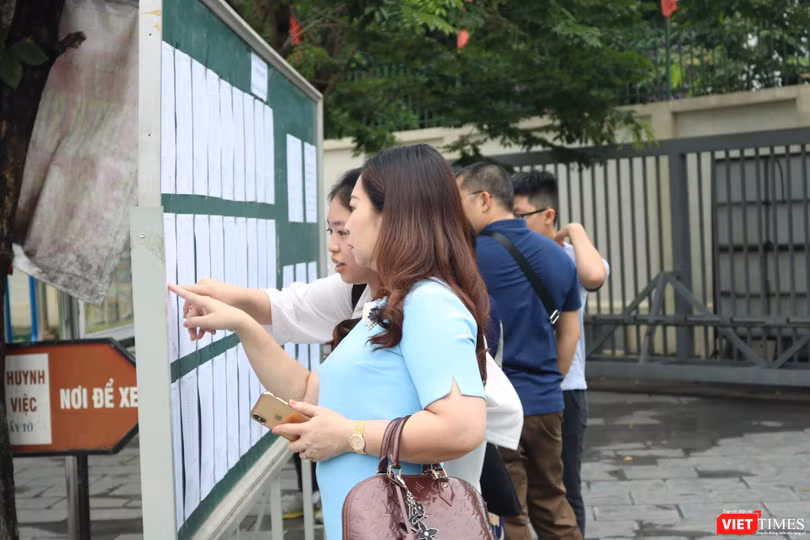 Học sinh và phụ huynh xem lịch thi. Ảnh: Minh Thúy