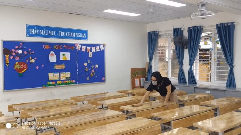 Cô giáo vệ sinh bàn học cho học sinh
