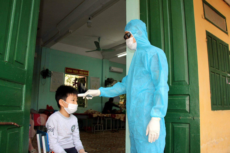 Nhân viên y tế đo nhiệt độ cho 1 em học sinh đang cách ly ở trường (Ảnh: BYT)