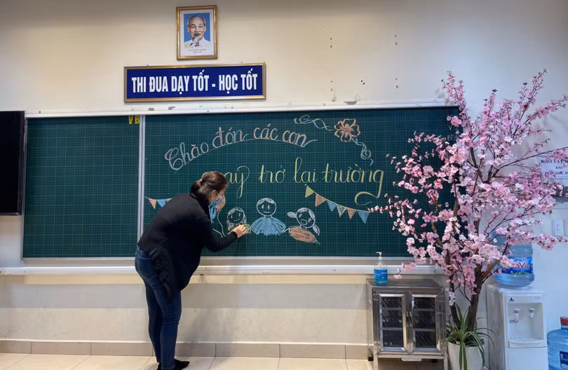 Cô giáo viết bảng chào đón học sinh quay trở lại trường (Ảnh - Phòng GD&ĐT quận Ba Đình) 